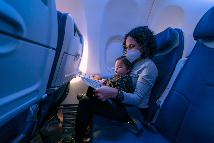 A mom on an airplane with her toddler on her lap.