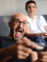 Father and son playing video games together at home.