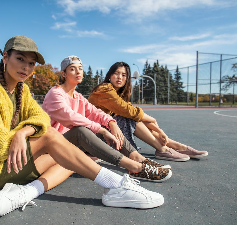 three friends pose for a photo as they sit on a tennis court and consider how the April 2023 hybrid ...