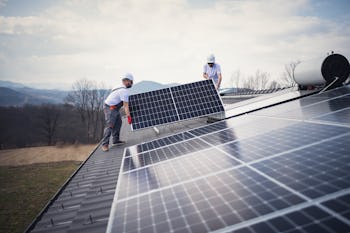 Workers on a house roof working on the installation of solar panels.