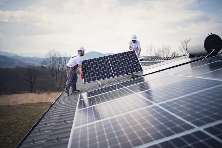 Workers on a house roof working on the installation of solar panels.