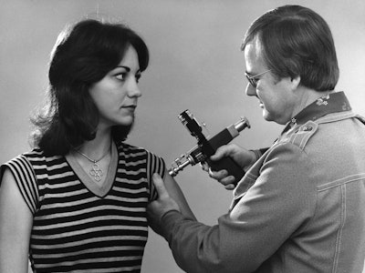 Public health worker vaccinating a young woman, with a jet injector, 1976. Image courtesy Centers fo...