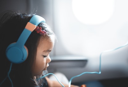 A cute toddler wearing headphones on an airplane, in a story answering the question, how does behavi...