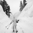 MAMMOTH LAKES, CA - MARCH 21: A skier walks between mounds of snow engulfing houses as heavy snow co...