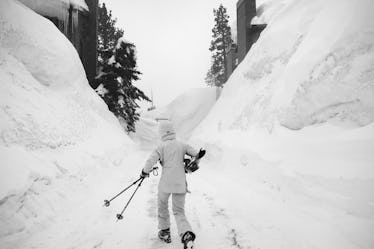 MAMMOTH LAKES, CA - MARCH 21: A skier walks between mounds of snow engulfing houses as heavy snow co...