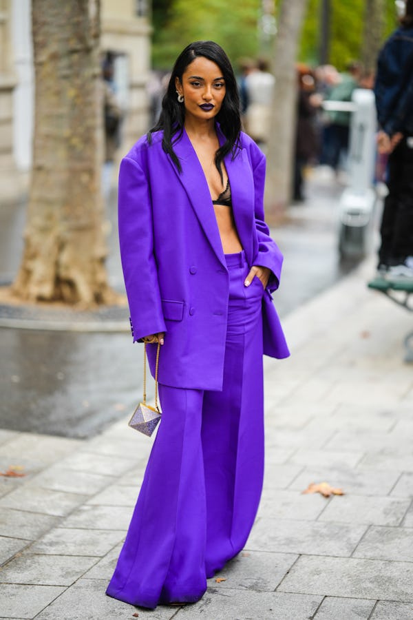 PARIS, FRANCE - OCTOBER 02: Amina Muaddi wears gold and diamonds earrings, a neon purple oversized b...