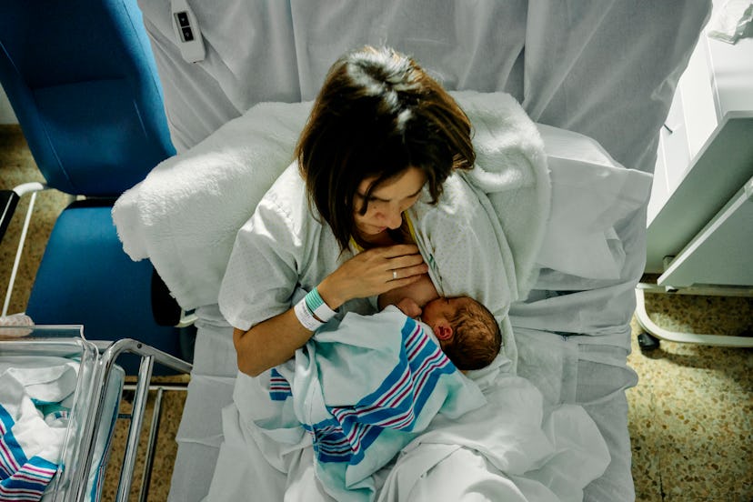 a mother breastfeeding her newborn at night in a hospital bed after giving birth seen from above