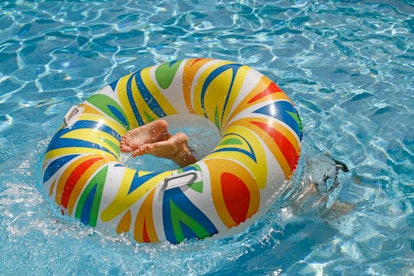 Boy jumping into inflatable ring at pool