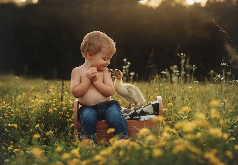photo of baby boy with ducklings in yellow flower field for article about april baby names