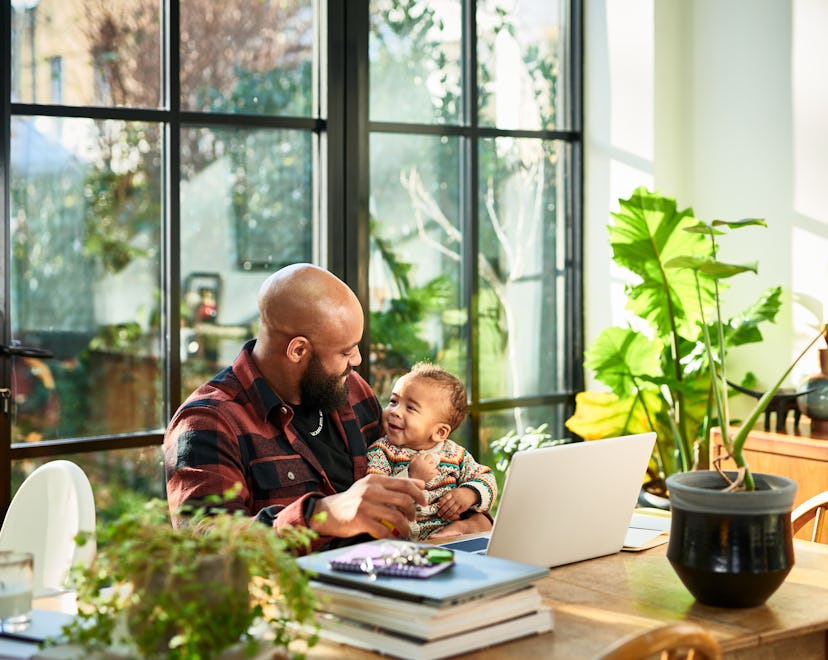 Father working from home with baby on knee,  in an article about what is generation alpha?