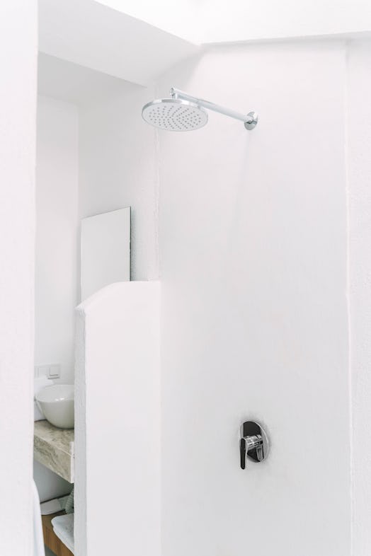 Empty shower in the hotel. White walls, vertical photo.