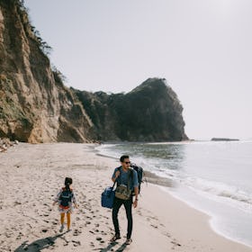 Father and child walking on beach with cliff, Tokyo Bay, Chiba, Japan