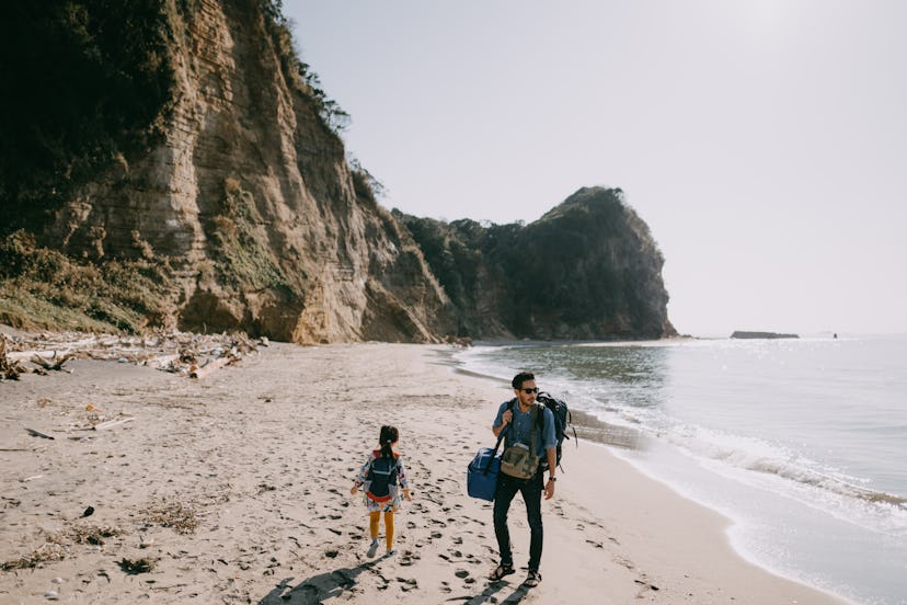 Father and child walking on beach with cliff, Tokyo Bay, Chiba, Japan