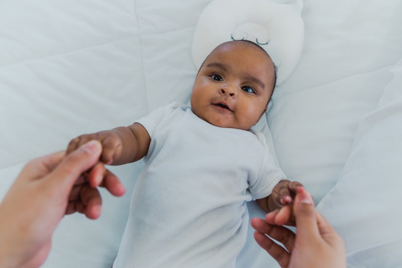 cute black baby laying on bed in article about baby names that mean lucky