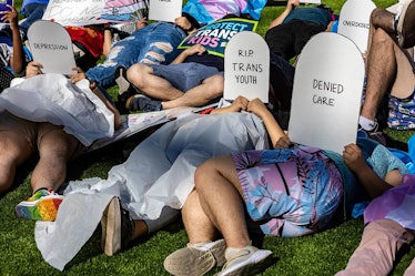 Protesters lie on the ground holding cardboard signs shaped like tombstones in front of the Marriott...