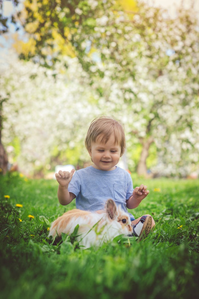 Happy child playing with bunny in article about baby names that mean lucky