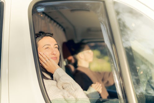 Heterosexual couple in love inside the campervan enjoying the sunlight and breathing fresh air,