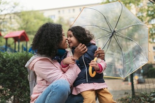 Mother with her little daughter at city walk during rain, near playground. A new study revealed what...