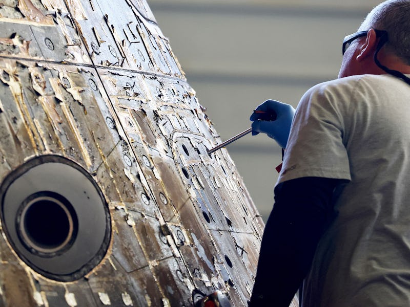 AT SEA, PACIFIC OCEAN - DECEMBER 12: A NASA engineer inspects the Orion Capsule in the well deck of ...