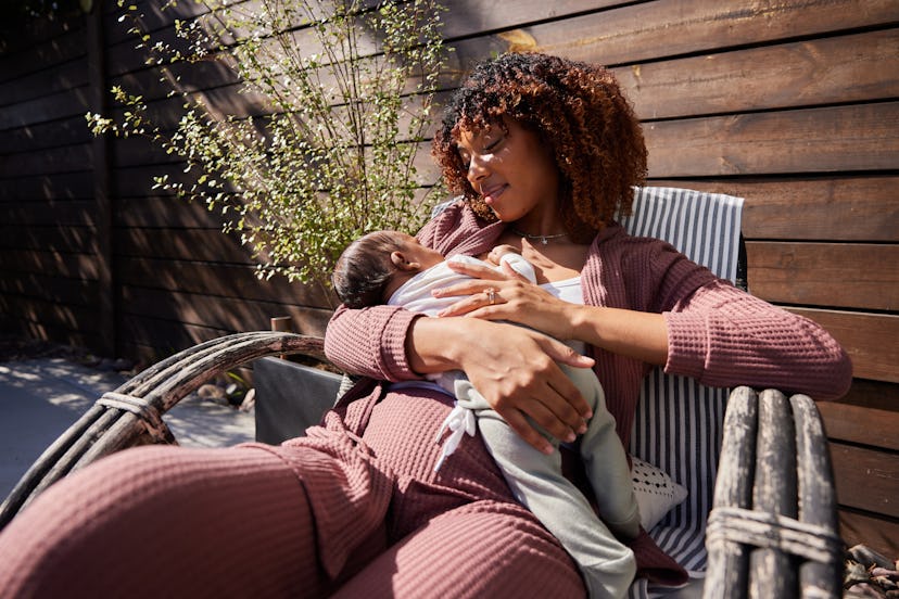 Mother smiling down at her baby boy while relaxing outside to help regulate her body clock because o...