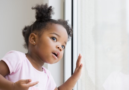 adorable young black girl looking out window in article about unique aries girl names 