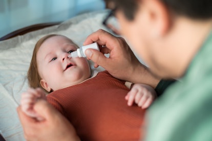 Parent uses saline on a baby while wondering, can you get sick from using the nose frida snot sucker...