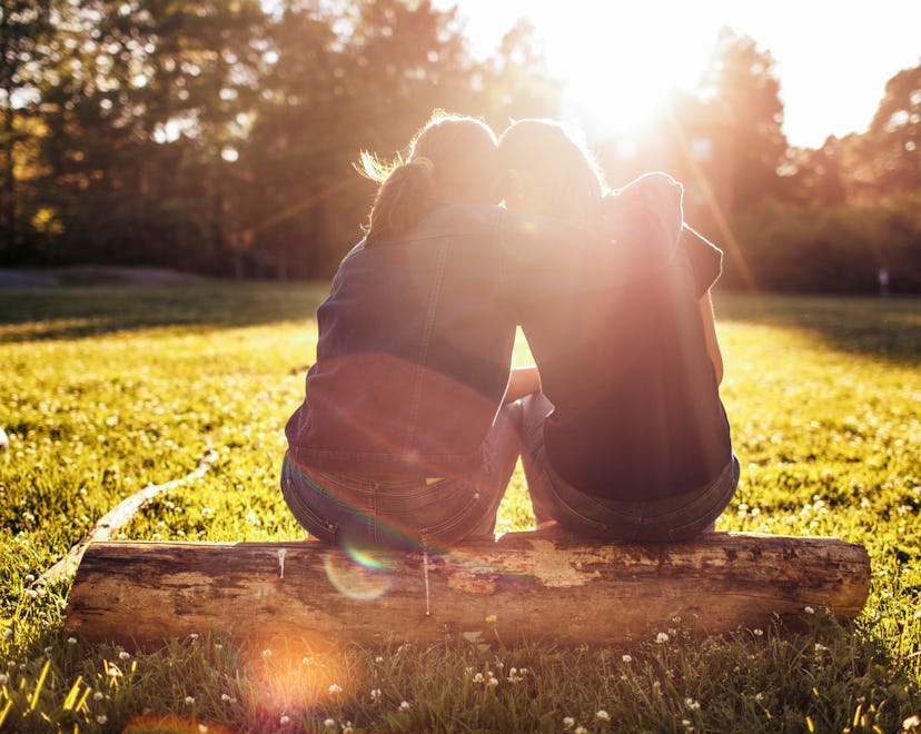 two woman hugging on a log in an article about what to say to someone who lost their mom