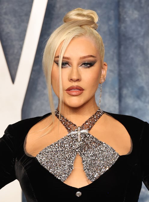 Christina Aguilera arrives at the 2023 Vanity Fair Oscar Party in a sleek top knot bun, a smokey eye...