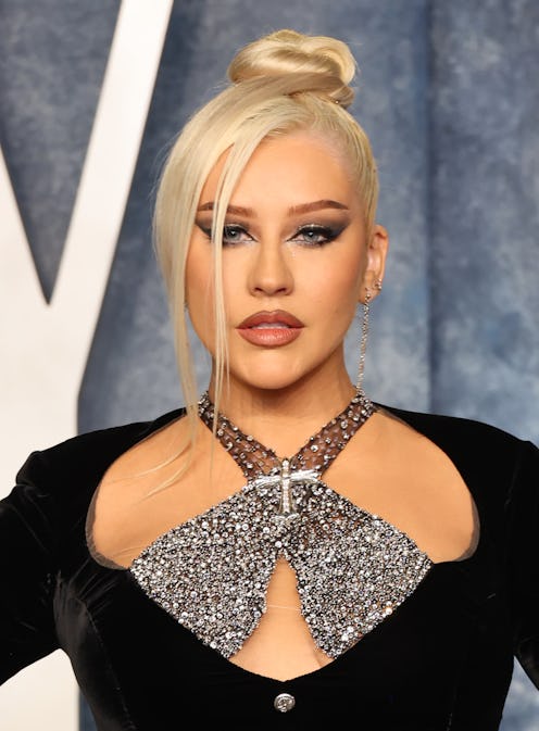 Christina Aguilera arrives at the 2023 Vanity Fair Oscar Party in a sleek top knot bun, a smokey eye...