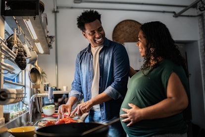Couple cooking together at home, in an article about should you celebrate mothers day if you're preg...