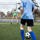 A soccer team practice game consisting of boys and girls on the field.  A female goalie defends a go...