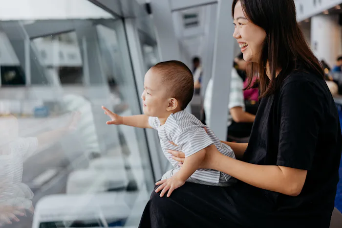 Image of an Asian Chinese baby boy looking out window for airplane at airport terminal