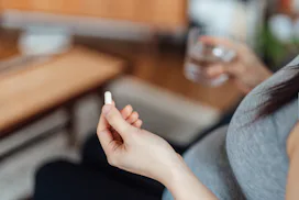 Can you take Tylenol while pregnant? Pregnant person holds up white tablet and glass of water.
