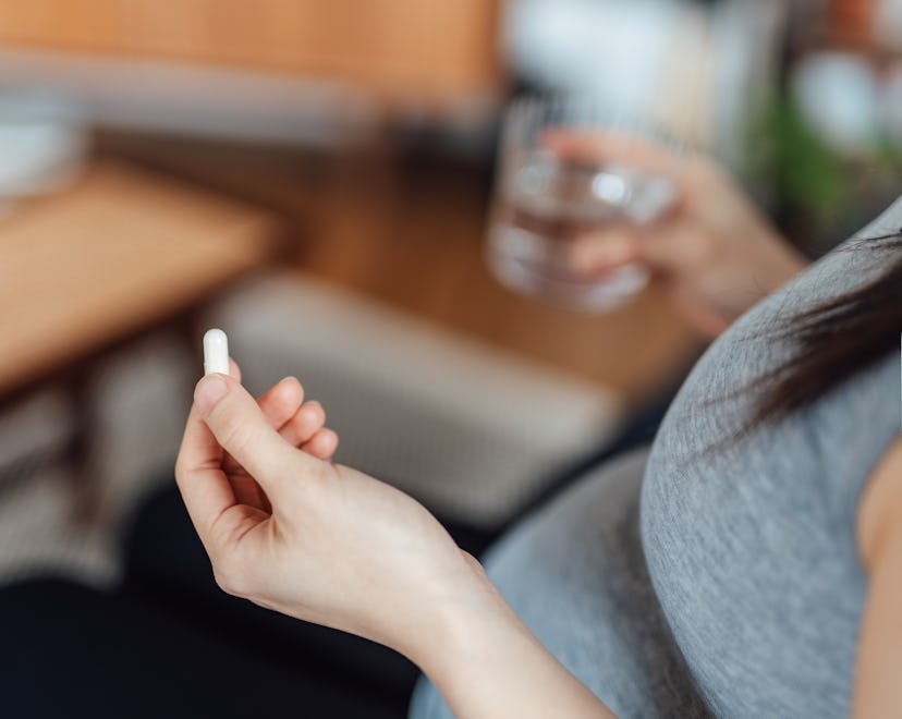 Can you take Tylenol while pregnant? Pregnant person holds up white tablet and glass of water.
