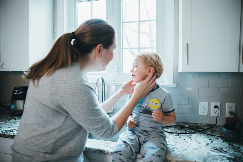 Mother checking son's ear in the kitchen, in a story about baby's ear infection causes and treatment...