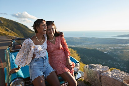two young women pose for a photo on a cliff, as they consider their May 2023 horoscope
