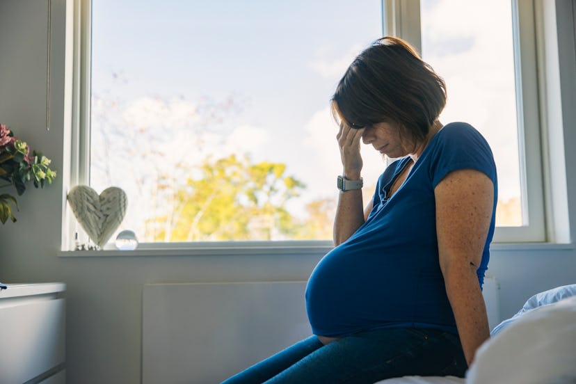 A pregnant woman sits on her bed, in a story answering the question, can you take tylenol while preg...