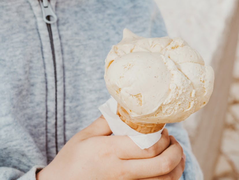 Closeup of boy hand holding cone ice cream outdoors