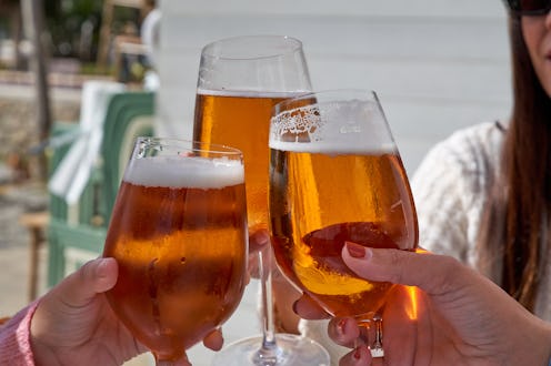 Three friends having a few beers and some tapas on the terrace of a beach bar. They are sitting arou...