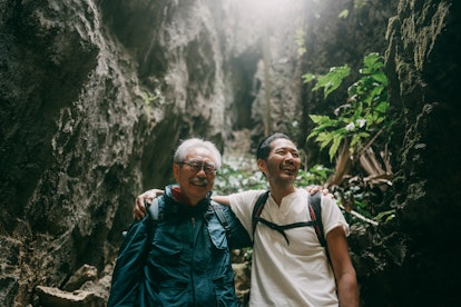 Senior father and adult son having fun in cave, Minami Daito Island, Okinawa, Japan