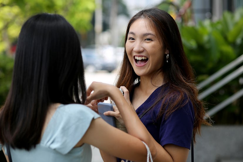 An Asian young woman is chatting with her female friend.
