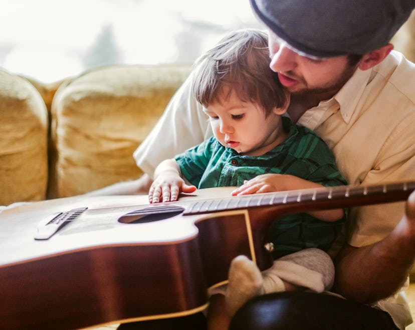 Music baby names are perfect for musicians, like this father letting his baby touch his guitar.