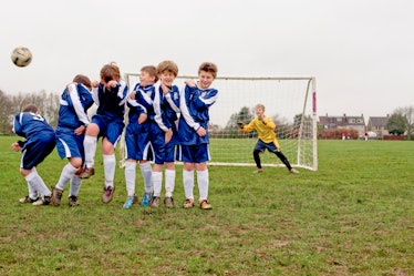 boys (10-12) football team line up to protect goal from a free kick