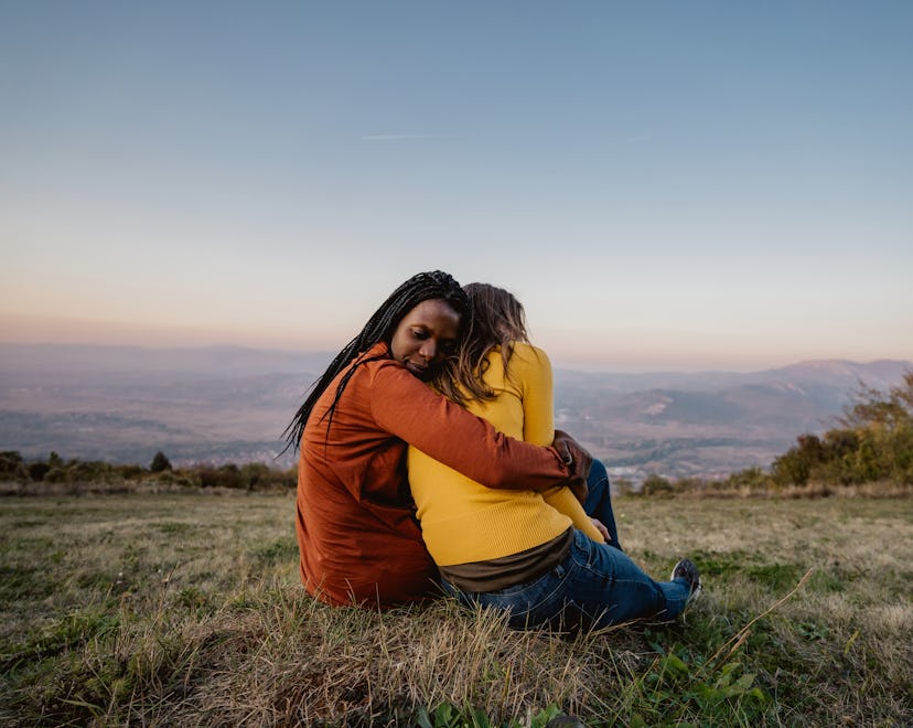 Friends sitting on meadow at sunset embracing. How to support someone who lost a child on mothers da...
