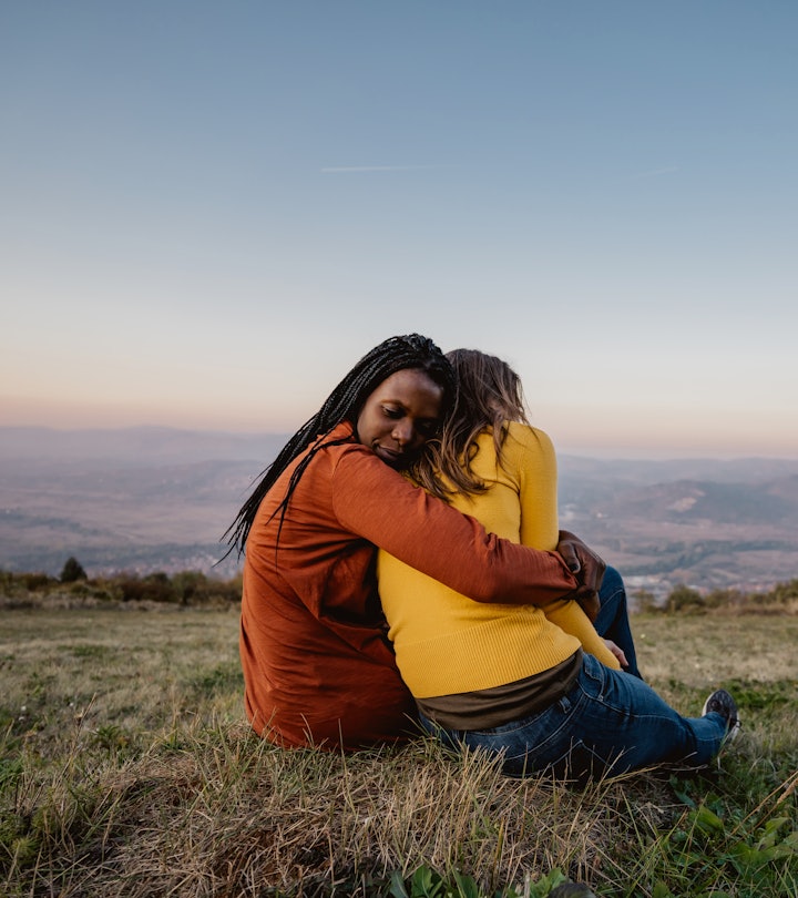 Friends sitting on meadow at sunset embracing. How to support someone who lost a child on mothers da...