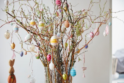 hang colorful egg ornaments from branches to decorate for an egg shower 