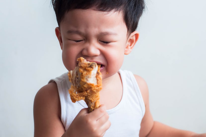 Head shot of male Southeast Asian toddler eating fried chicken on a white background. can babies eat...