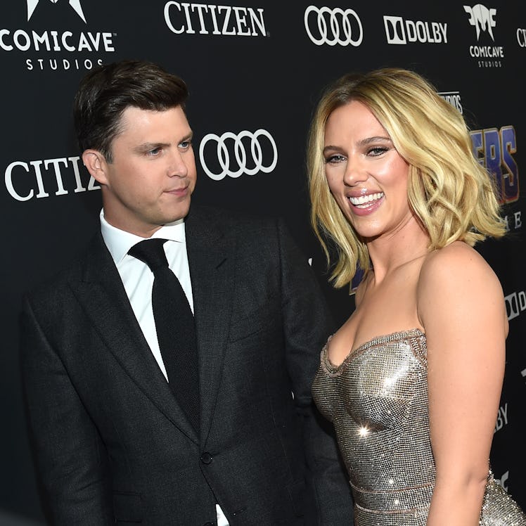 Colin Jost in a black suit and Scarlett Johansson in a silver dress.