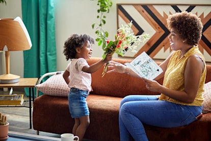 Little girl hands her smiling mom a Mother's Day card and bouquet, in a story about what to do on Mo...
