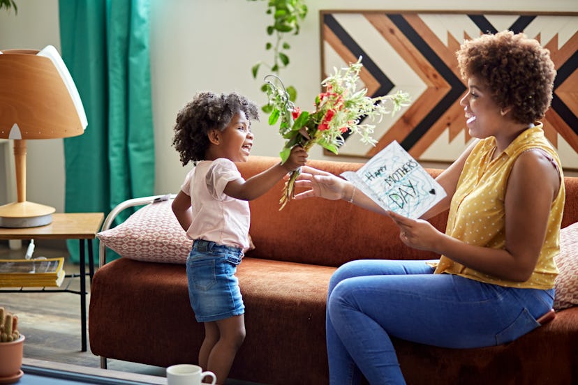 Little girl hands her smiling mom a Mother's Day card and bouquet, in a story about what to do on Mo...